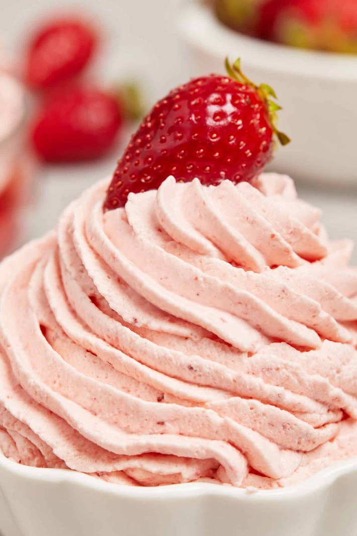 Bowl of fresh red strawberries topped with whipped cream